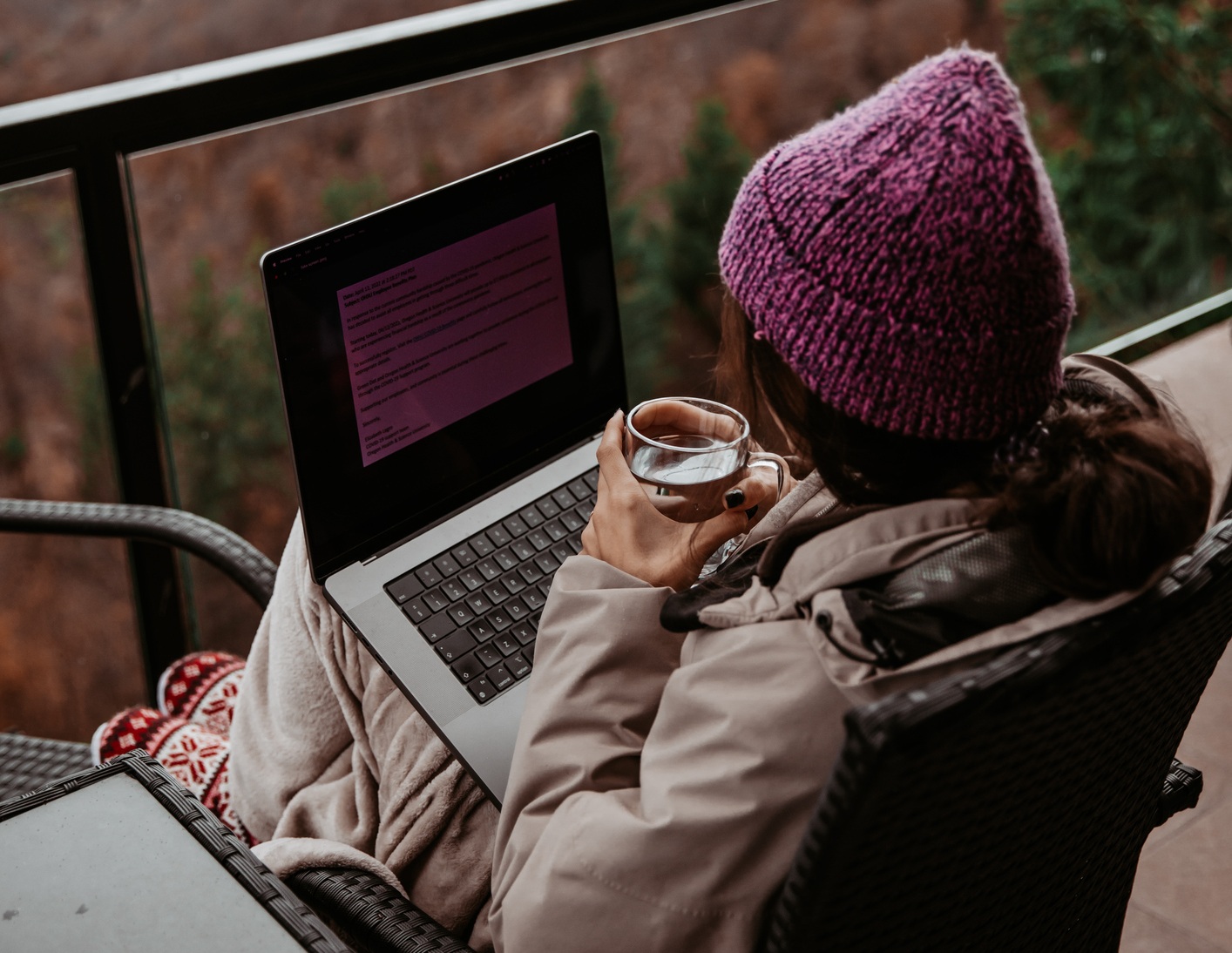 A young woman is working remotely from a mountain house.