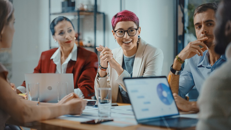 Office Meeting in Conference Room: Beautiful Specialist with Short Pink Hair Talks about Firm Strategy with Diverse Team of Professional Business people.